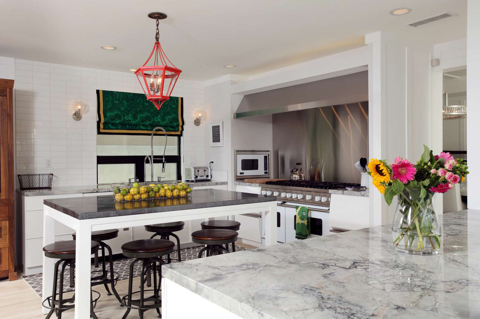 This is an example of a contemporary kitchen in Los Angeles with metallic splashback, metal splashback, light hardwood floors and white appliances.