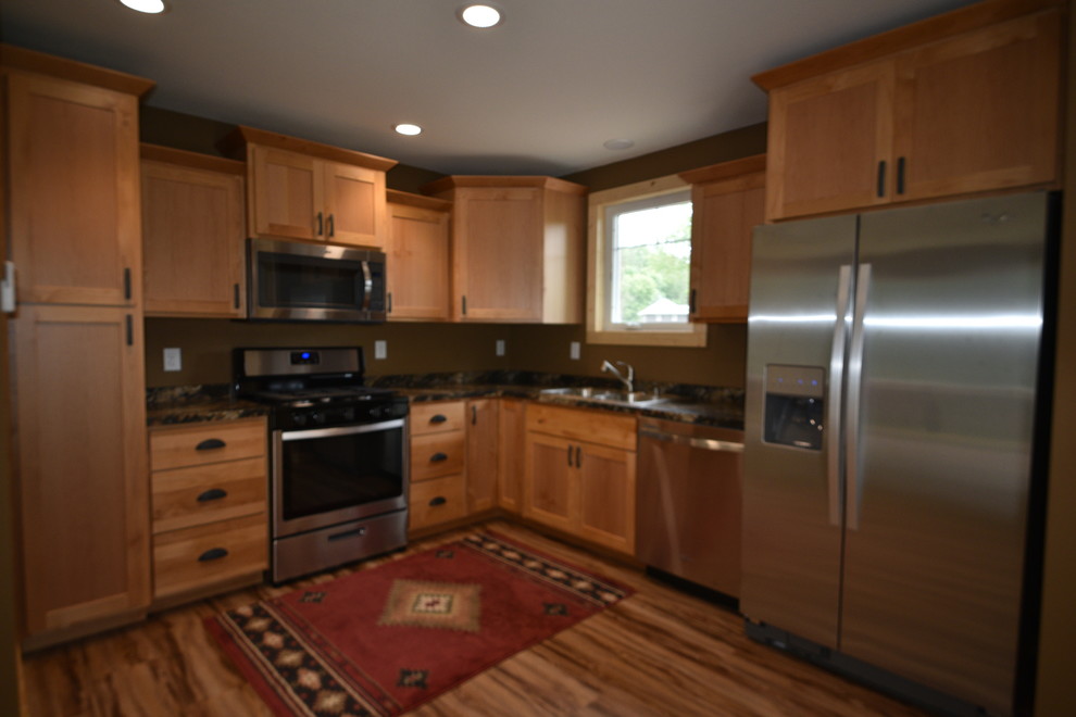 Eat-in kitchen - mid-sized rustic l-shaped eat-in kitchen idea in Minneapolis with flat-panel cabinets, light wood cabinets, granite countertops, black backsplash and no island