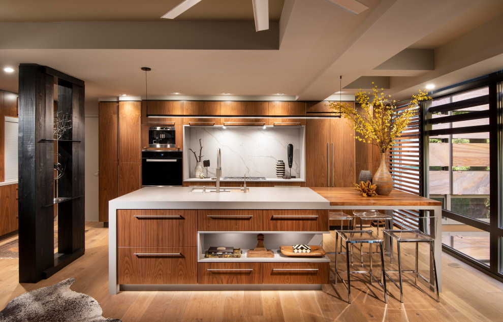 Photo of a contemporary galley kitchen in Phoenix with a submerged sink, flat-panel cabinets, medium wood cabinets, stainless steel appliances, medium hardwood flooring, an island, brown floors, white worktops and a drop ceiling.