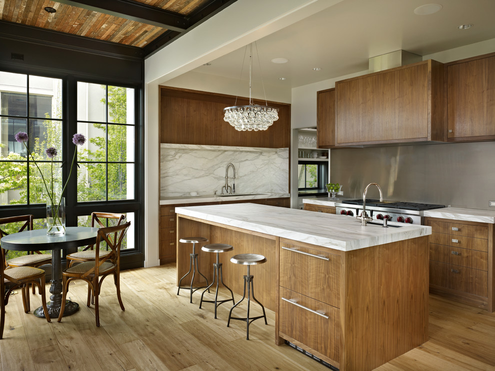 Contemporary eat-in kitchen in Seattle with flat-panel cabinets, medium wood cabinets, white splashback, stone slab splashback and stainless steel appliances.