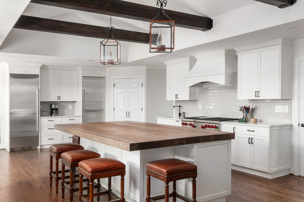 This is an example of a large transitional kitchen in Atlanta with shaker cabinets, white cabinets, grey splashback, stainless steel appliances, with island, wood benchtops, subway tile splashback and medium hardwood floors.