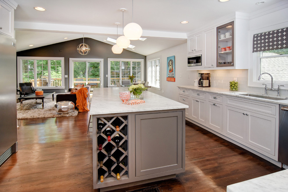 Mid-sized transitional u-shaped dark wood floor open concept kitchen photo in Newark with an undermount sink, beaded inset cabinets, white cabinets, marble countertops, white backsplash, glass tile backsplash, stainless steel appliances and an island