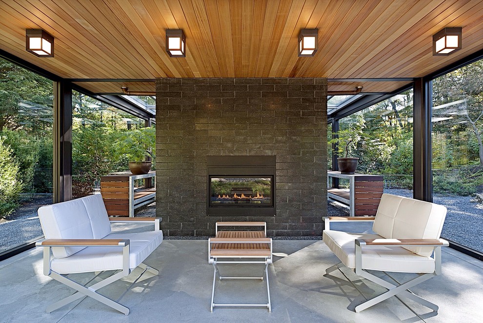 Small modern backyard patio in Boston with a fire feature, concrete slab and a roof extension.