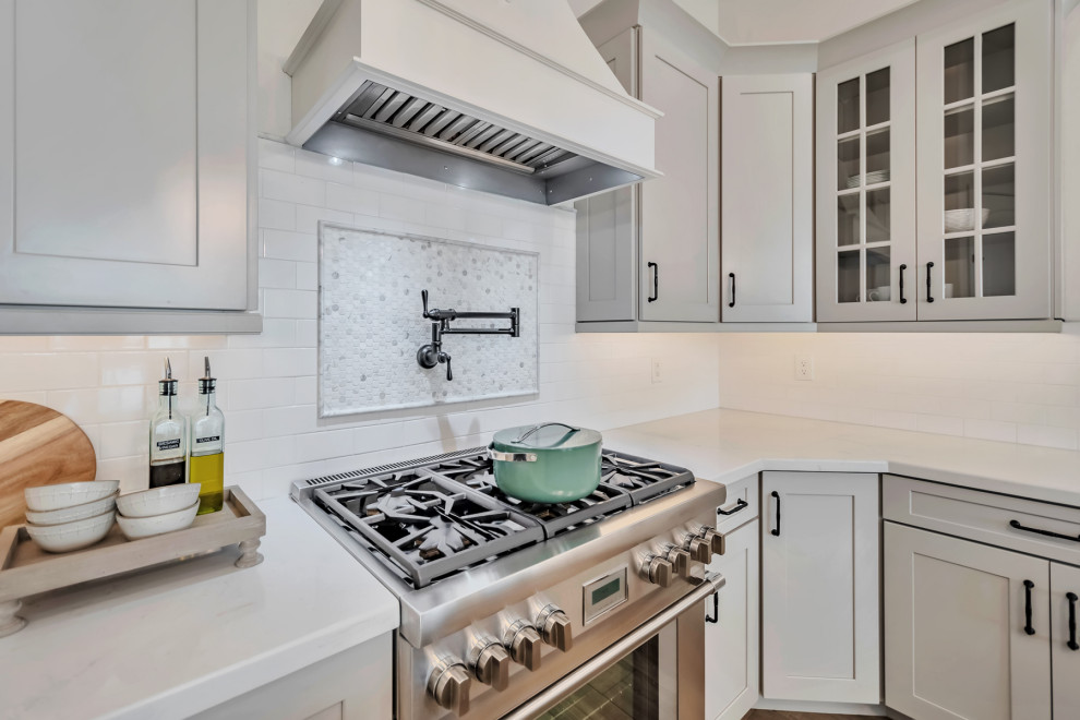 Large transitional u-shaped porcelain tile, brown floor and exposed beam kitchen photo in Phoenix with a farmhouse sink, shaker cabinets, gray cabinets, quartzite countertops, white backsplash, porcelain backsplash, stainless steel appliances, an island and white countertops