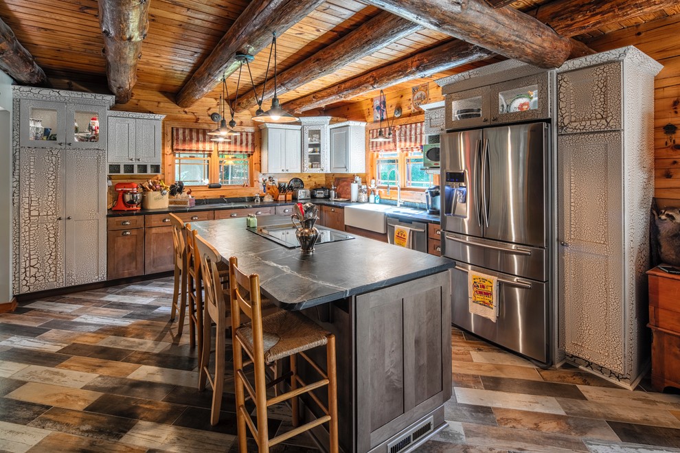 Design ideas for a country l-shaped kitchen in New York with a farmhouse sink, shaker cabinets, dark wood cabinets, timber splashback, stainless steel appliances, with island, multi-coloured floor and black benchtop.