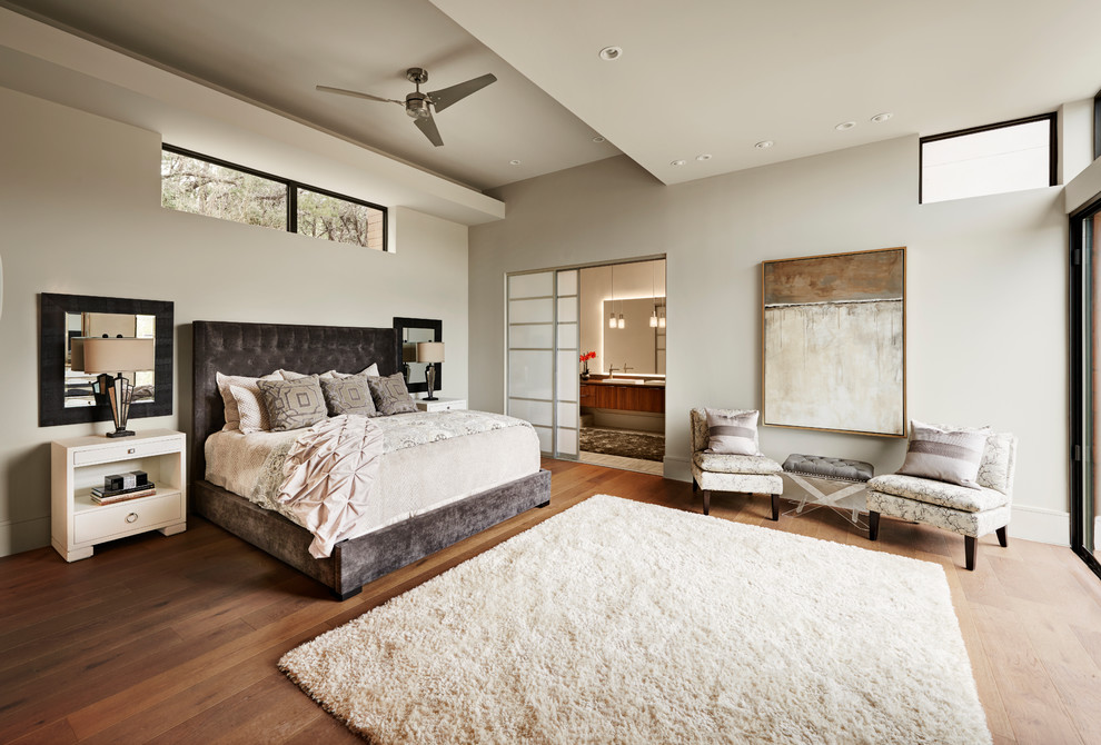 Photo of a large contemporary master bedroom in Austin with white walls, medium hardwood floors and no fireplace.