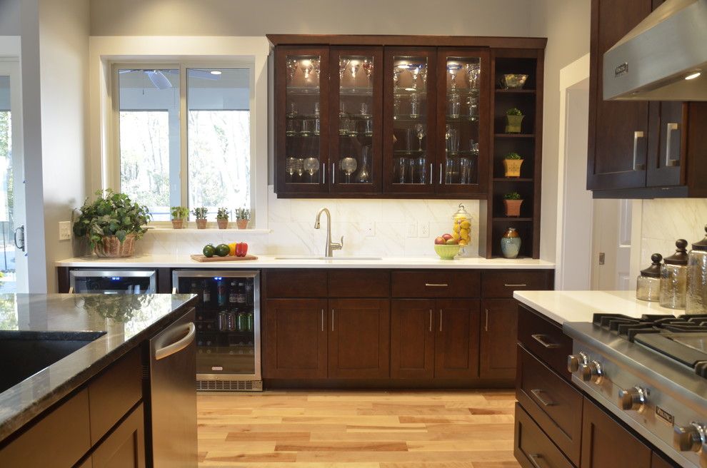 Open concept kitchen - large transitional u-shaped light wood floor open concept kitchen idea with an island, an undermount sink, shaker cabinets, dark wood cabinets, quartz countertops, white backsplash, stone tile backsplash and stainless steel appliances