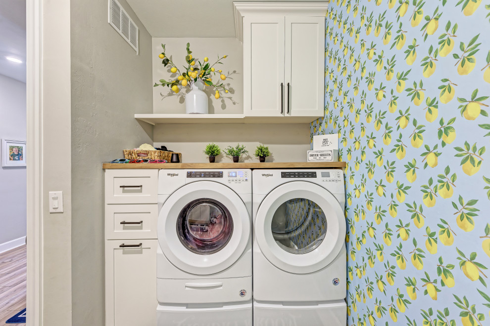 タンパにある高級な広いカントリー風のおしゃれな洗濯室 (ll型、白いキャビネット、セラミックタイルの床、左右配置の洗濯機・乾燥機、グレーの床) の写真