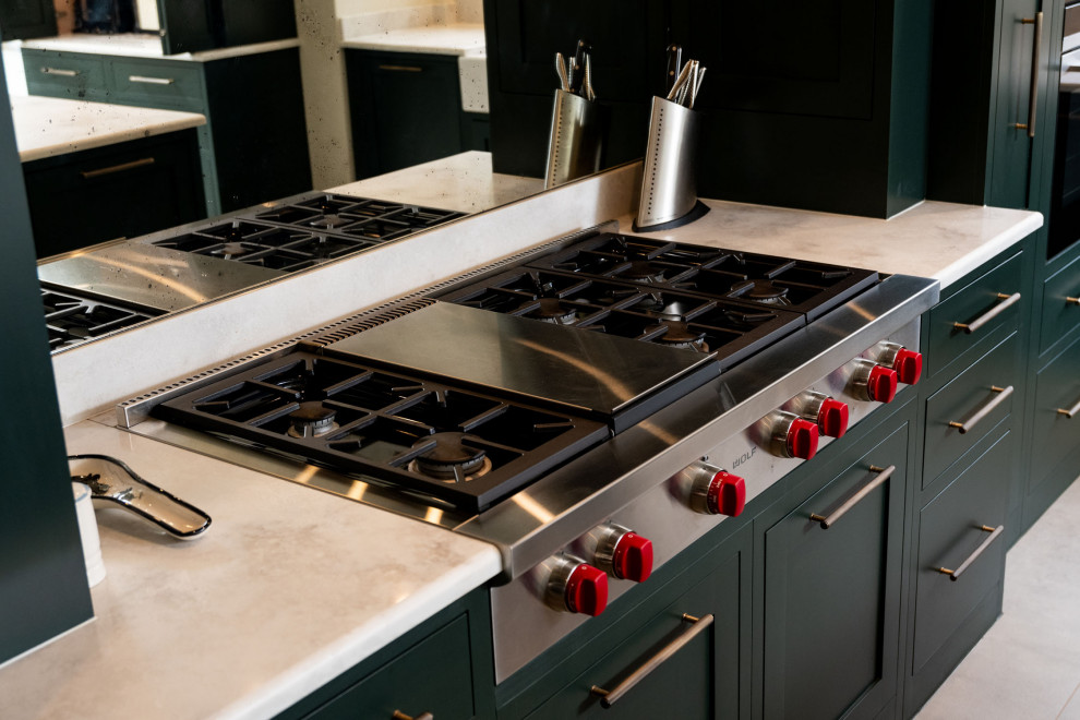 Inspiration for a large industrial l-shaped open plan kitchen in Essex with a farmhouse sink, flat-panel cabinets, green cabinets, quartzite benchtops, metallic splashback, mirror splashback, stainless steel appliances, limestone floors, with island, grey floor and grey benchtop.