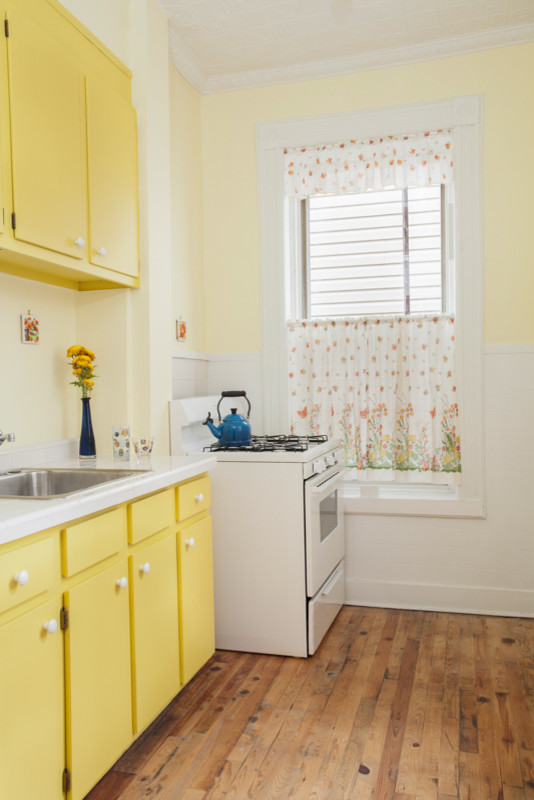Inspiration for a small midcentury galley separate kitchen in New York with a drop-in sink, flat-panel cabinets, yellow cabinets, tile benchtops, yellow splashback, porcelain splashback, white appliances, light hardwood floors and no island.