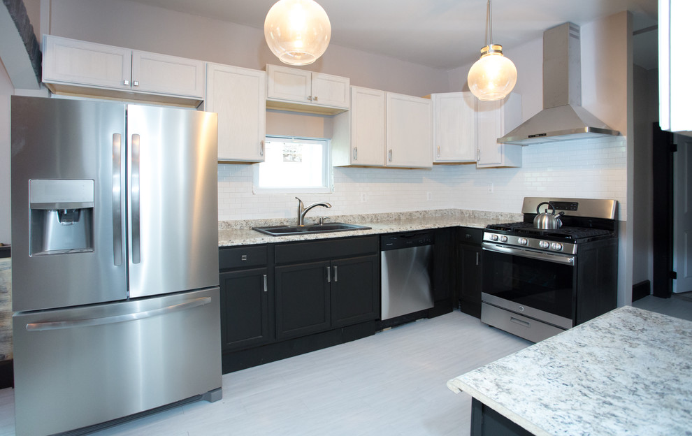 Small transitional l-shaped vinyl floor and white floor enclosed kitchen photo with a double-bowl sink, recessed-panel cabinets, black cabinets, laminate countertops, white backsplash, subway tile backsplash, stainless steel appliances and gray countertops