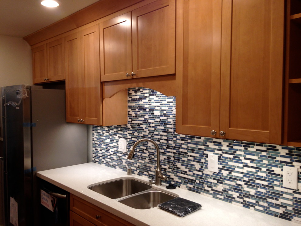Photo of a small contemporary galley separate kitchen in San Francisco with an undermount sink, shaker cabinets, medium wood cabinets, quartz benchtops, blue splashback, glass sheet splashback, stainless steel appliances, bamboo floors and no island.