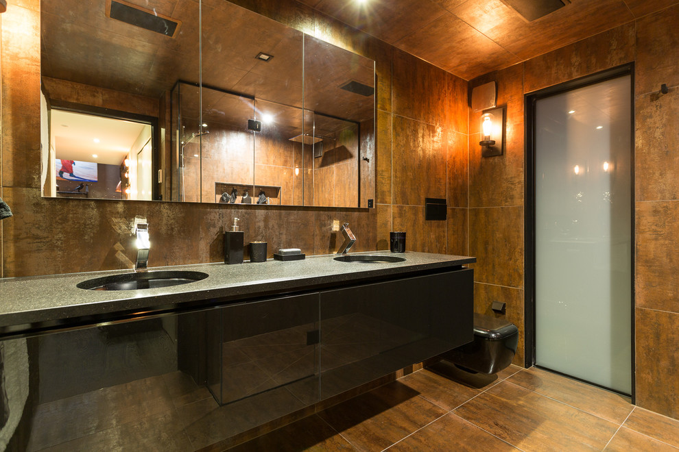 This is an example of a mid-sized industrial master bathroom in Auckland with black cabinets, a double shower, a wall-mount toilet, brown tile, metal tile, brown walls, an undermount sink and granite benchtops.