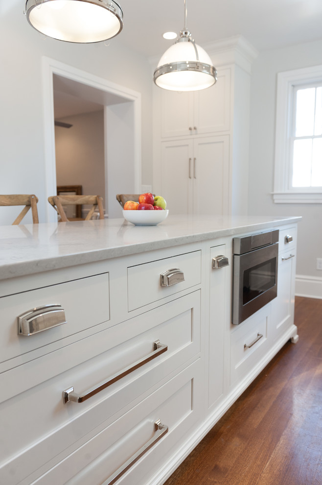 Design ideas for a small transitional single-wall separate kitchen in Wilmington with a farmhouse sink, white cabinets, quartz benchtops, white splashback, subway tile splashback, stainless steel appliances, medium hardwood floors, with island and brown floor.