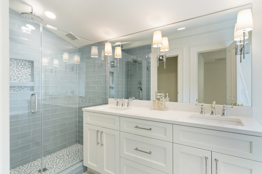 This is an example of a mid-sized traditional master bathroom in Atlanta with shaker cabinets, white cabinets, a freestanding tub, a two-piece toilet, blue tile, glass tile, white walls, ceramic floors, an undermount sink, solid surface benchtops, a hinged shower door, white benchtops, an enclosed toilet, a double vanity, a freestanding vanity, vaulted and white floor.
