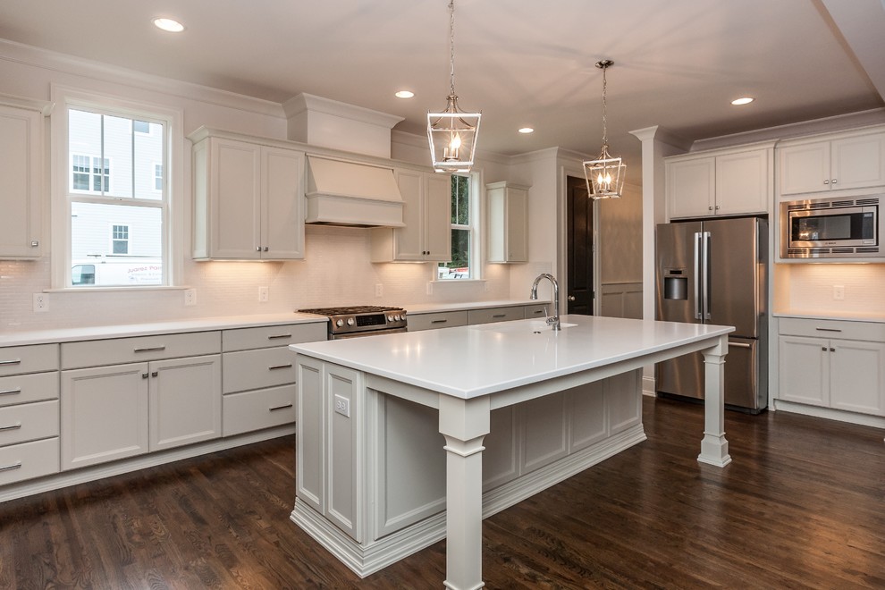 Design ideas for a large contemporary l-shaped kitchen in Raleigh with an undermount sink, recessed-panel cabinets, white cabinets, quartz benchtops, white splashback, mosaic tile splashback, stainless steel appliances, dark hardwood floors and with island.