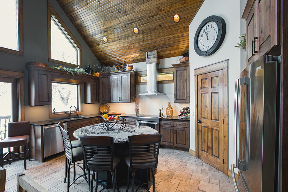 Inspiration for a rustic porcelain tile kitchen remodel with an undermount sink, raised-panel cabinets, distressed cabinets, granite countertops and stainless steel appliances