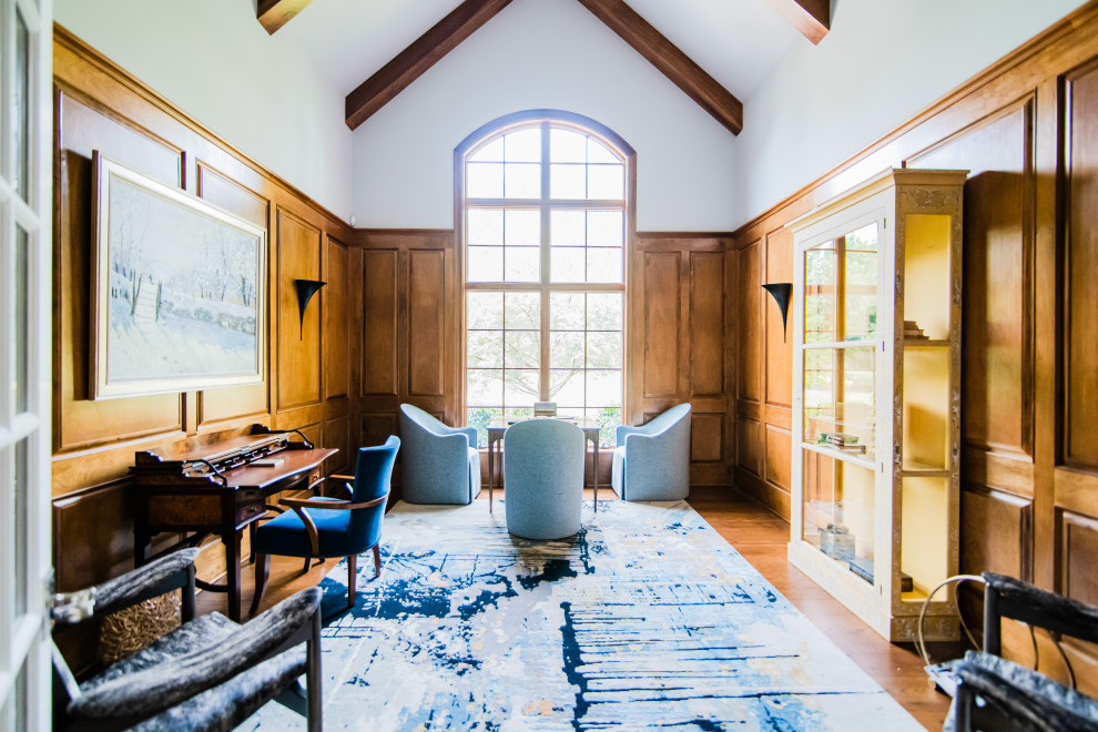 Großes Klassisches Lesezimmer mit grauer Wandfarbe, braunem Holzboden, freistehendem Schreibtisch, braunem Boden, gewölbter Decke und Holzwänden in Charlotte