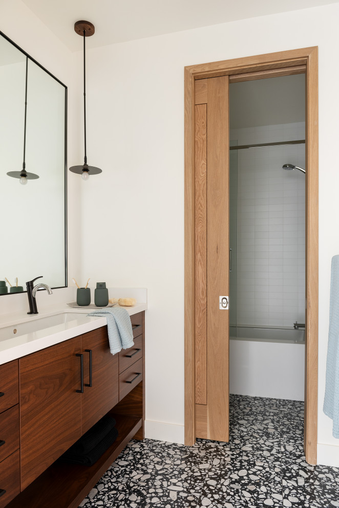 This is an example of a mid-sized country kids bathroom in Other with flat-panel cabinets, dark wood cabinets, an undermount tub, white tile, ceramic tile, white walls, ceramic floors, a trough sink, engineered quartz benchtops, black floor, a sliding shower screen, white benchtops and a shower/bathtub combo.