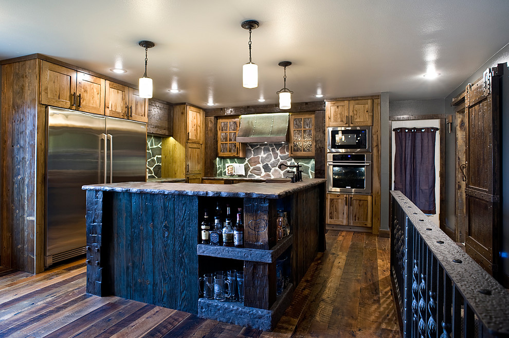 Example of a large mountain style l-shaped dark wood floor and brown floor enclosed kitchen design with a farmhouse sink, shaker cabinets, dark wood cabinets, wood countertops, multicolored backsplash, stone tile backsplash, stainless steel appliances and an island