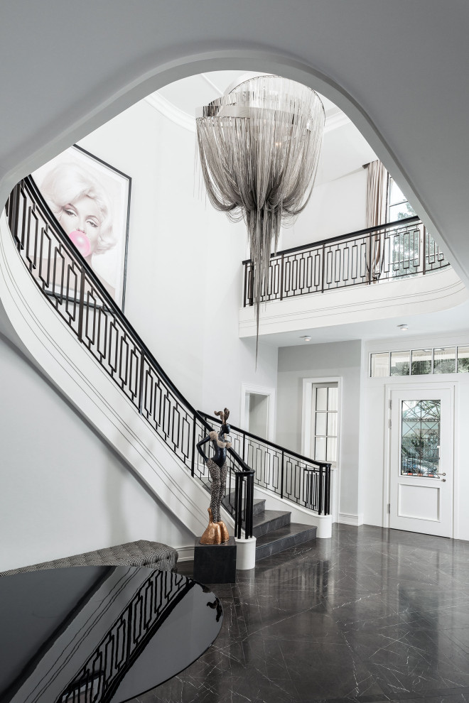 This is an example of a large traditional marble curved staircase in Berlin with marble risers and metal railing.