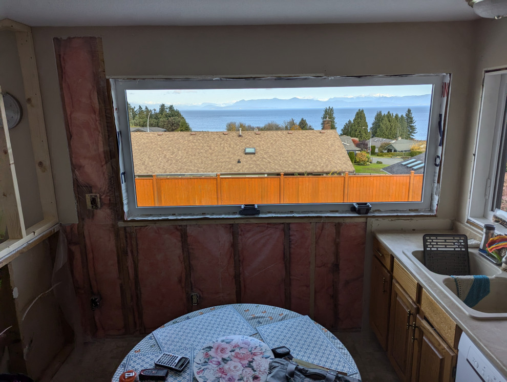 Kitchen remodel in progress with ocean-facing window and stripped interior walls