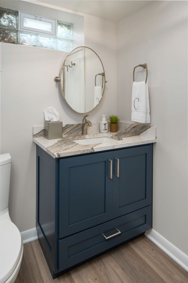 Mid-sized transitional 3/4 bathroom in Columbus with shaker cabinets, blue cabinets, a two-piece toilet, white walls, vinyl floors, an undermount sink, engineered quartz benchtops, grey floor, multi-coloured benchtops, a single vanity and a built-in vanity.