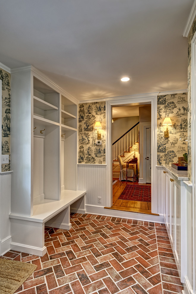 Photo of a mid-sized traditional single-wall utility room in New York with shaker cabinets, white cabinets, beige walls, brick floors, a side-by-side washer and dryer and brown floor.