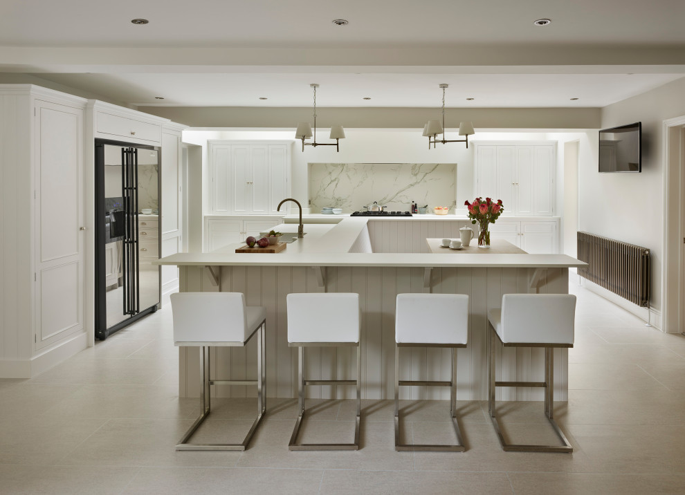 Inspiration for an expansive transitional l-shaped open plan kitchen in Other with with island, white benchtop, a farmhouse sink, shaker cabinets, grey splashback, porcelain floors and beige floor.