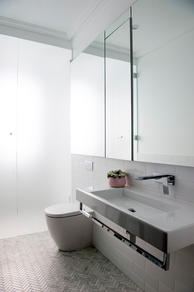 Design ideas for a mid-sized traditional wet room bathroom in Sydney with glass-front cabinets, a wall-mount toilet, white tile, subway tile, white walls, marble floors, a wall-mount sink, white floor, a hinged shower door and white benchtops.