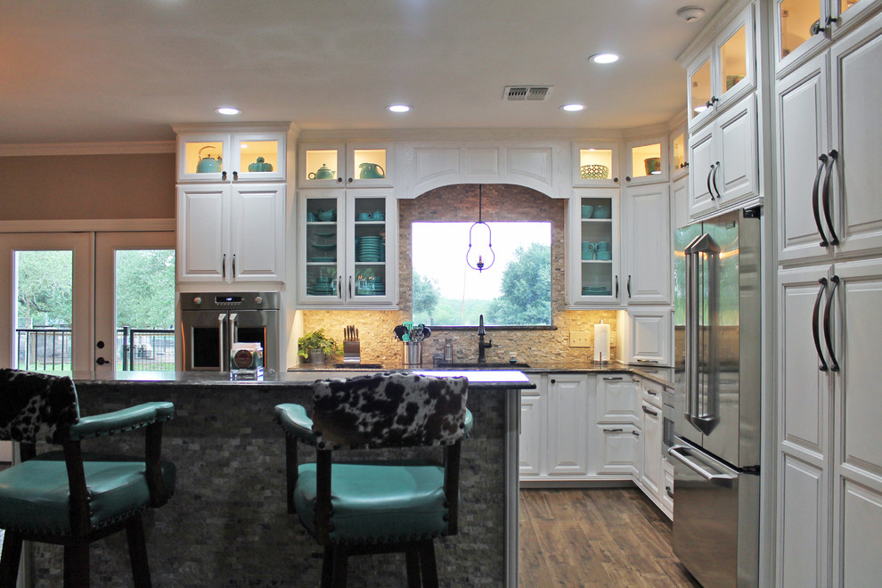 Design ideas for a mid-sized country l-shaped eat-in kitchen in Austin with an undermount sink, raised-panel cabinets, white cabinets, quartz benchtops, beige splashback, stone tile splashback, stainless steel appliances, porcelain floors and with island.