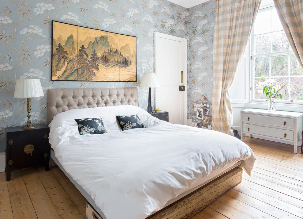 This is an example of a mid-sized eclectic master bedroom in Edinburgh with multi-coloured walls, medium hardwood floors and brown floor.