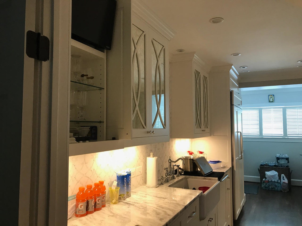 Mid-sized transitional l-shaped brown floor and dark wood floor enclosed kitchen photo in DC Metro with an undermount sink, shaker cabinets, white cabinets, marble countertops, white backsplash, subway tile backsplash, paneled appliances and an island