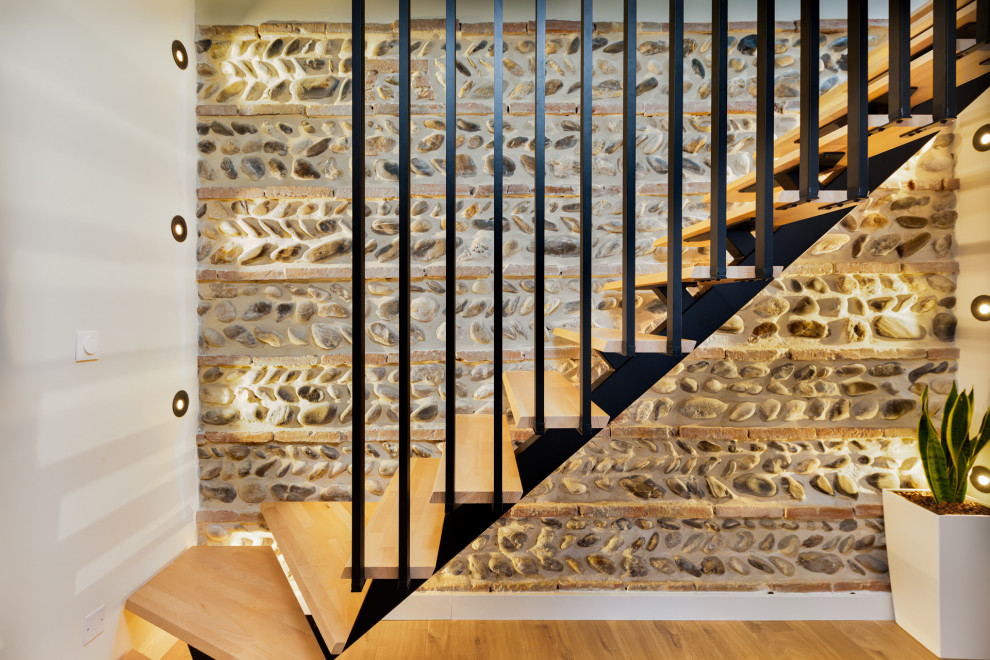 Réalisation d'un petit escalier flottant minimaliste avec des marches en bois, un garde-corps en métal, un mur en parement de brique et éclairage.