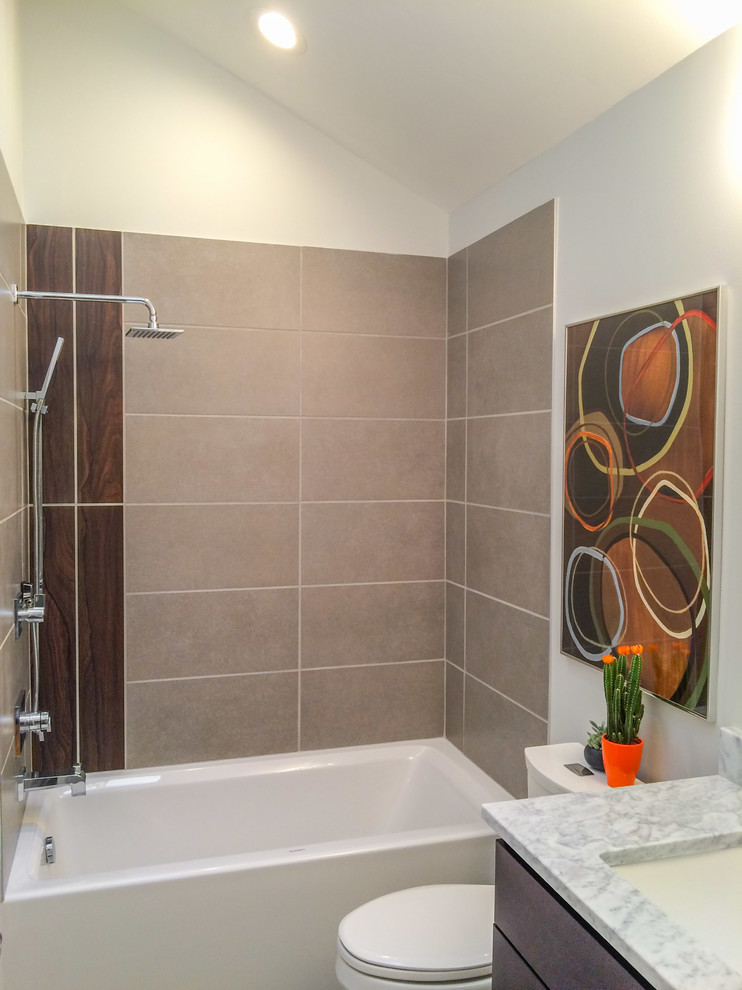 Photo of a small contemporary bathroom in Raleigh with flat-panel cabinets, dark wood cabinets, an alcove tub, a shower/bathtub combo, a two-piece toilet, gray tile, porcelain tile, grey walls, porcelain floors, an undermount sink and marble benchtops.