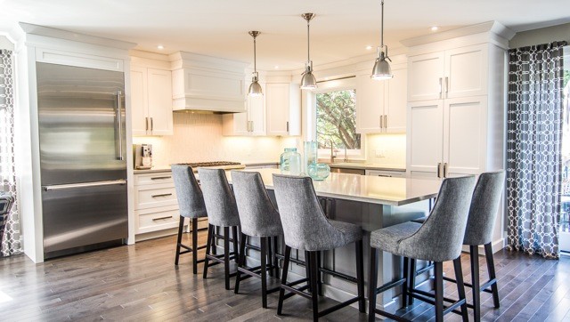 Mid-sized contemporary l-shaped eat-in kitchen in Toronto with a double-bowl sink, shaker cabinets, white cabinets, quartz benchtops, grey splashback, stainless steel appliances, medium hardwood floors and with island.