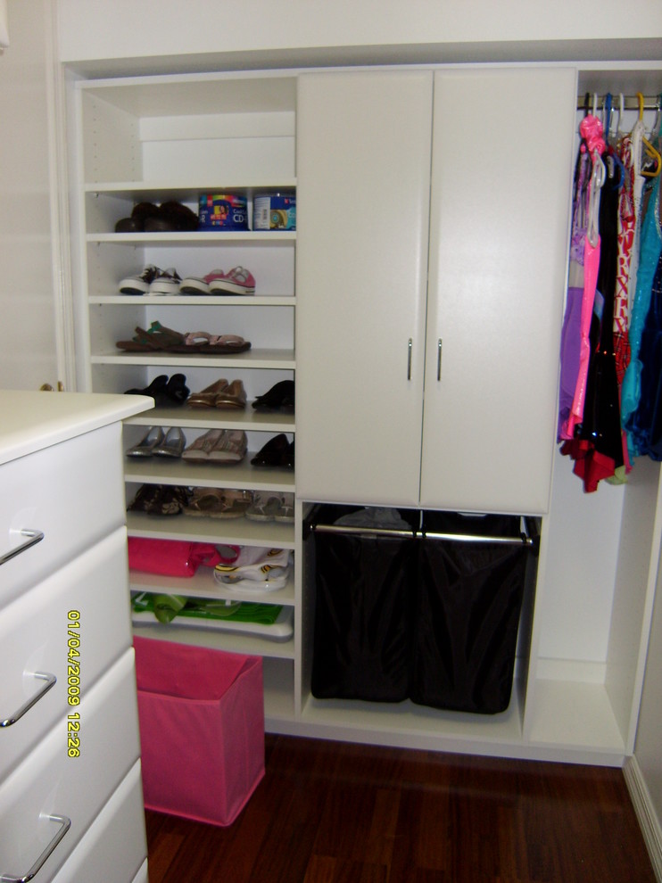 Photo of a small traditional women's walk-in wardrobe in Tampa with white cabinets, flat-panel cabinets and dark hardwood floors.