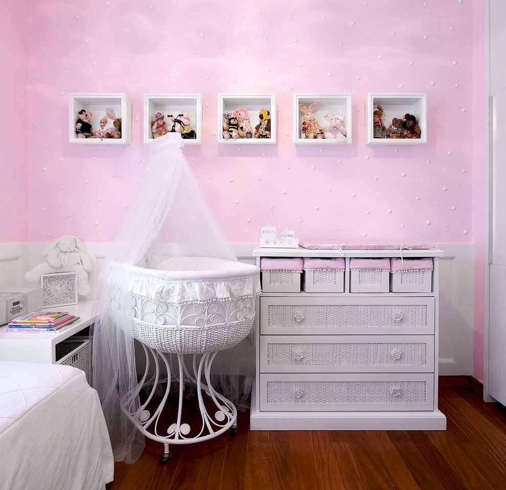 This is an example of a mid-sized traditional nursery for girls in Other with pink walls and dark hardwood floors.