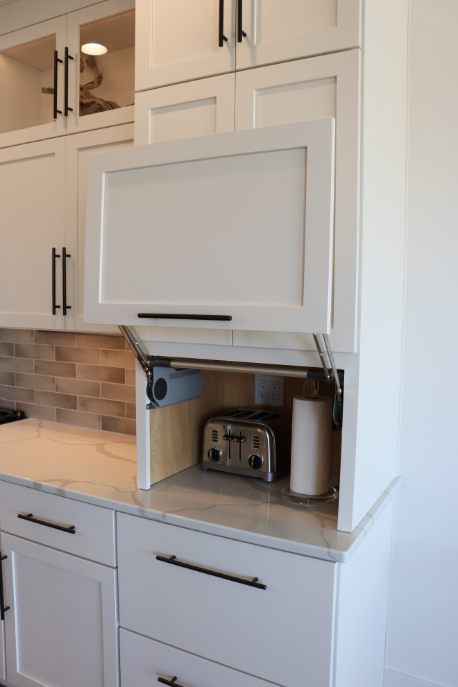 Inspiration for a large transitional l-shaped medium tone wood floor and brown floor open concept kitchen remodel with a single-bowl sink, shaker cabinets, white cabinets, quartz countertops, gray backsplash, subway tile backsplash, stainless steel appliances, an island and white countertops