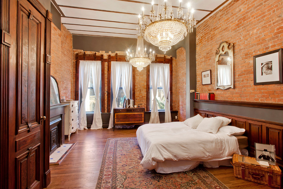 Large eclectic master bedroom in New York with grey walls, medium hardwood floors, a standard fireplace and a stone fireplace surround.