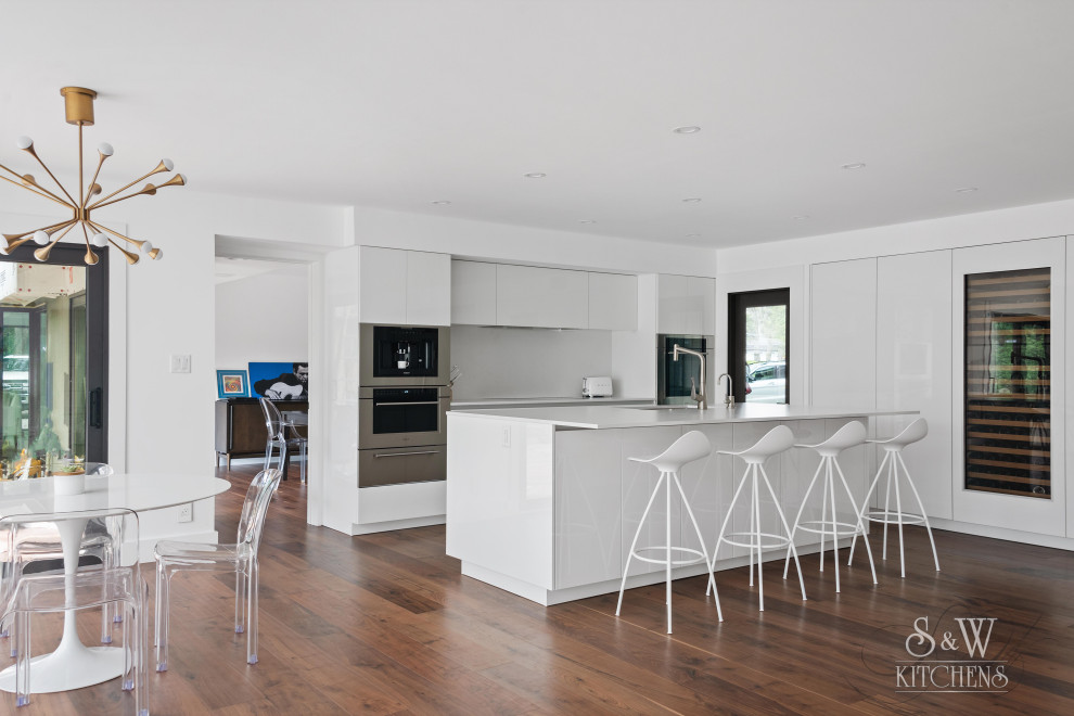 Design ideas for a mid-sized contemporary l-shaped open plan kitchen in Tampa with a single-bowl sink, flat-panel cabinets, white cabinets, quartz benchtops, white splashback, engineered quartz splashback, panelled appliances, medium hardwood floors, with island, brown floor and white benchtop.