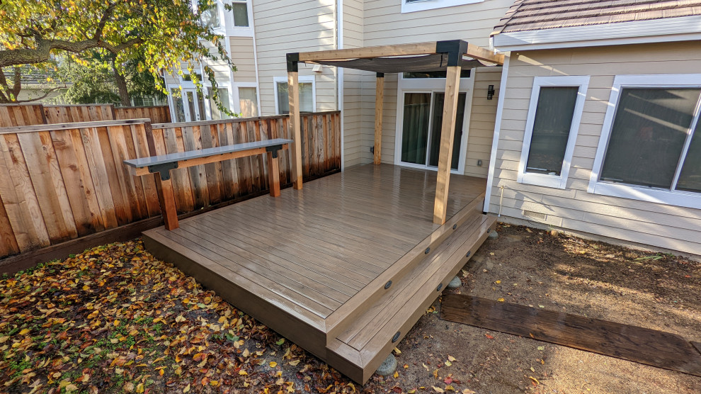 Photo of a small modern backyard and ground level deck in Other with a pergola.