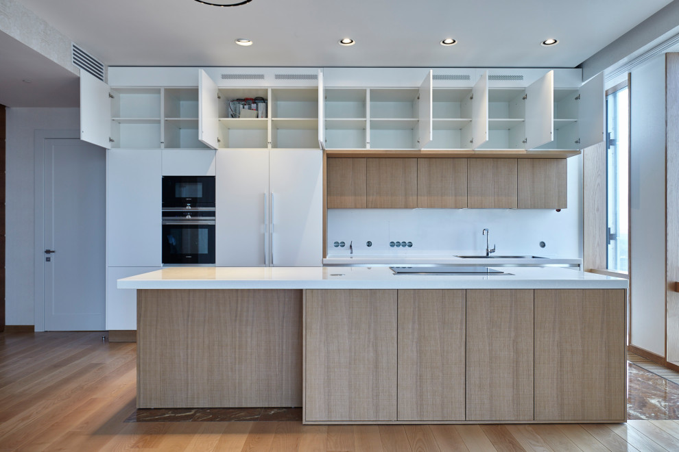 Photo of a large contemporary single-wall eat-in kitchen in Moscow with a double-bowl sink, white cabinets, white splashback, laminate floors, with island, brown floor and white benchtop.