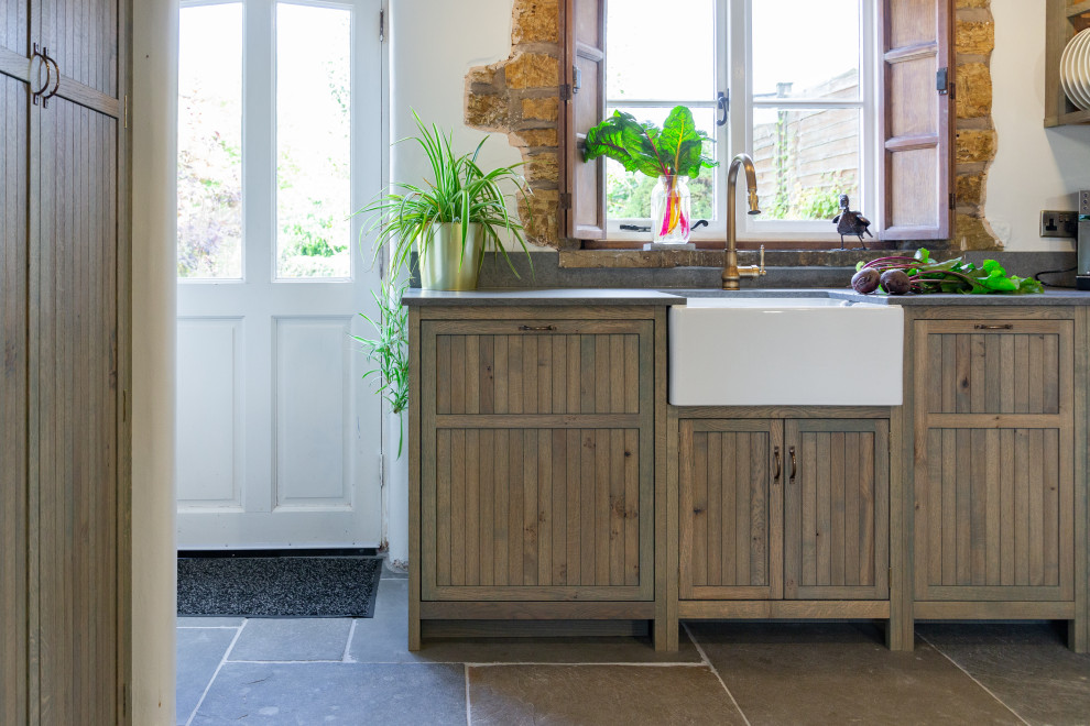 Design ideas for a mid-sized country galley eat-in kitchen in West Midlands with a farmhouse sink, shaker cabinets, green cabinets, quartzite benchtops, grey splashback, engineered quartz splashback, panelled appliances, slate floors, no island, grey floor, grey benchtop and exposed beam.