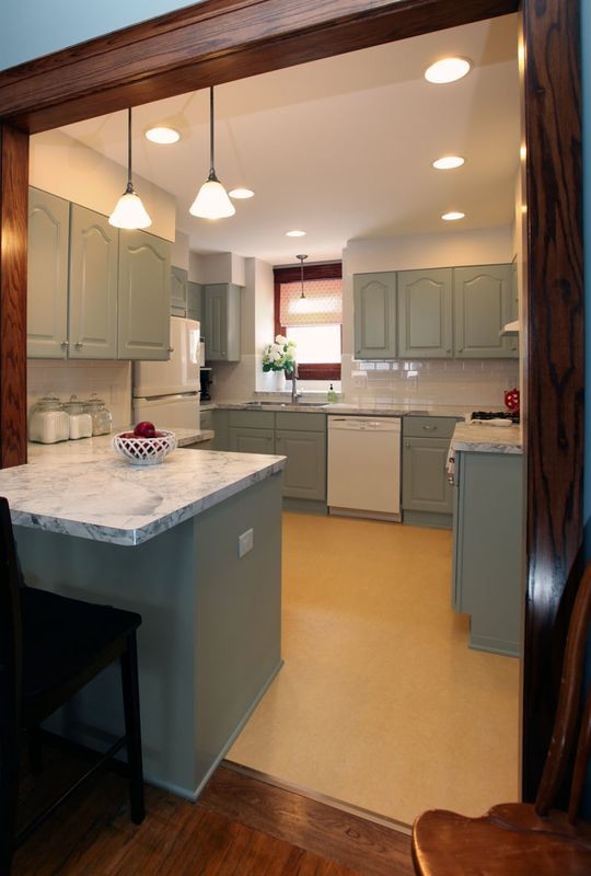 This is an example of a traditional u-shaped eat-in kitchen in Minneapolis with an integrated sink, raised-panel cabinets, grey cabinets, laminate benchtops, white splashback, subway tile splashback and white appliances.