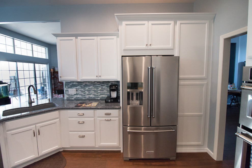 Open concept kitchen - mid-sized transitional u-shaped porcelain tile and brown floor open concept kitchen idea with an undermount sink, recessed-panel cabinets, white cabinets, quartz countertops, blue backsplash, mosaic tile backsplash, stainless steel appliances and blue countertops