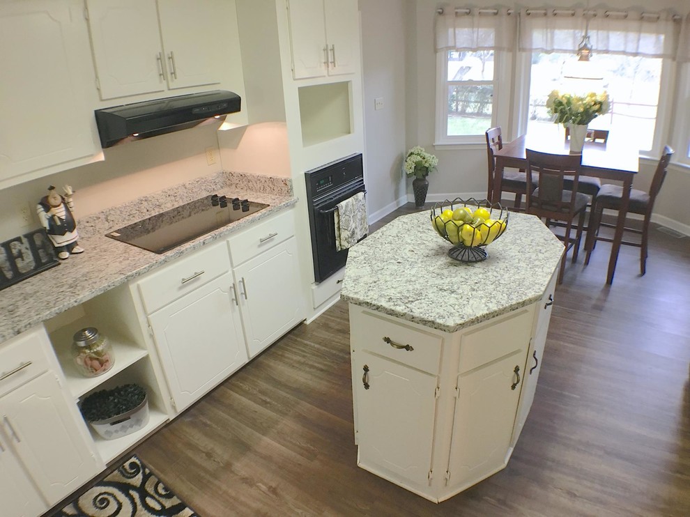 Photo of a mid-sized traditional u-shaped eat-in kitchen in San Diego with an undermount sink, flat-panel cabinets, yellow cabinets, granite benchtops, white splashback, black appliances, vinyl floors and with island.