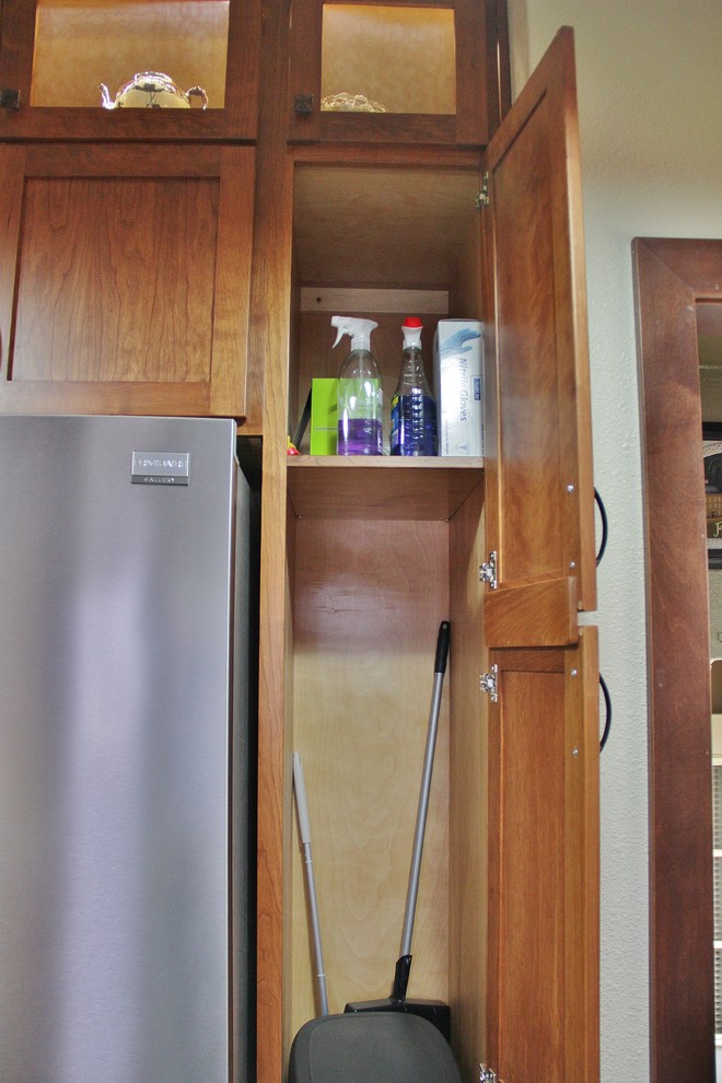 Example of a mid-sized transitional galley ceramic tile enclosed kitchen design with an undermount sink, shaker cabinets, medium tone wood cabinets, quartz countertops, beige backsplash, stone tile backsplash, stainless steel appliances and a peninsula
