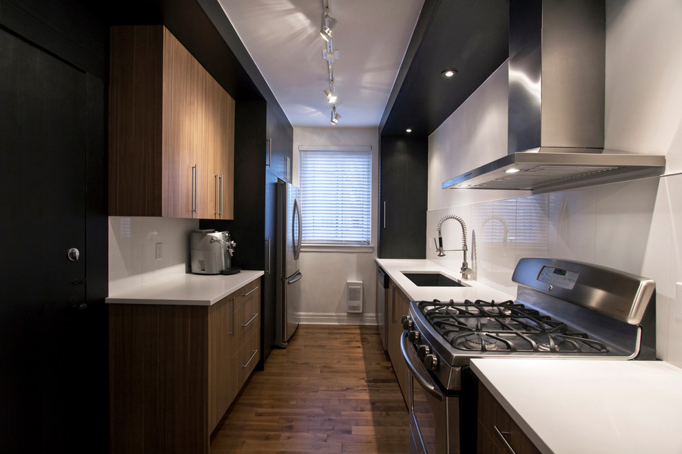 Inspiration for a mid-sized contemporary galley separate kitchen in Montreal with an undermount sink, flat-panel cabinets, black cabinets, quartzite benchtops, white splashback, porcelain splashback, stainless steel appliances, medium hardwood floors and no island.