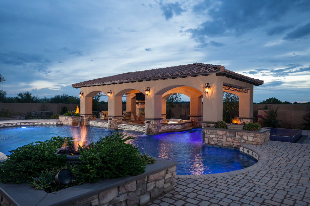 Inspiration for a large mediterranean backyard kidney-shaped natural pool in Phoenix with a pool house and brick pavers.